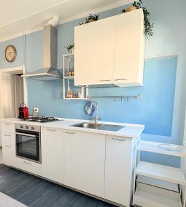 a kitchen with white cabinets and a sink at CLUA Holiday House in Porto Ceresio
