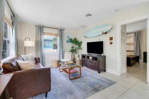 a living room with a couch and a tv at Cottage 3 on Penn - Pool in West Palm Beach