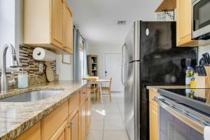 a kitchen with wooden cabinets and a stainless steel refrigerator at Cottage 3 on Penn - Pool in West Palm Beach +24 photos