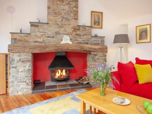 a living room with a red couch and a fireplace at Mill Bank No 8 - Uk33902 in Ashsprington