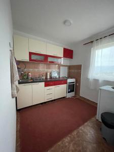 a small kitchen with white cabinets and red accents at L&L in Sarajevo