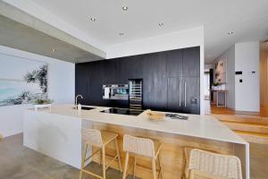 a kitchen with a large white island with chairs at Riva - Oceanfront, Heated pool, 3 bathrooms, Sleeps 8 in Bargara