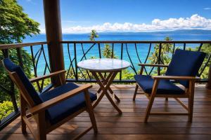 a balcony with a table and chairs and the ocean at Luxury Ocean View Villa, Savusavu Bay, Blue Bayou Bure with Starlink in Savusavu