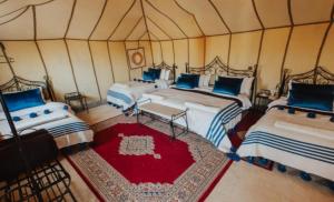 a room with four beds in a tent at Desert Paradise Luxury Camp in Merzouga