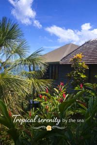 a house with a palm tree and flowers at Luxury Ocean View Villa, Savusavu Bay, Blue Bayou Bure with Starlink in Savusavu
