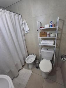 a bathroom with a toilet and a sink with a shower curtain at Excellent Monoambiente in Santos Lugares