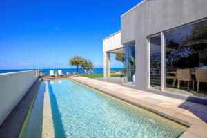 a swimming pool in front of a house at Riva - Oceanfront, Heated pool, 3 bathrooms, Sleeps 8 in Bargara
