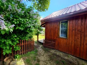 a wooden cabin with a fence next to a tree at Domek Jabłoniowy in Małe Leżno +3 photos