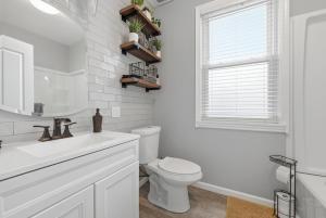 a white bathroom with a toilet and a window at Bright & Clean 2BR Near Downtown Porch Parking in Pittsburgh +20 photos