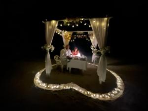 a couple sitting at a table under a gazebo with lights at REEF SHINE Thoddoo in Thoddoo
