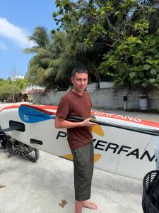 a man is standing next to a surfboard at REEF SHINE Thoddoo in Thoddoo