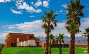 a building with palm trees and mountains in the background at Bab Sma in Oumnas