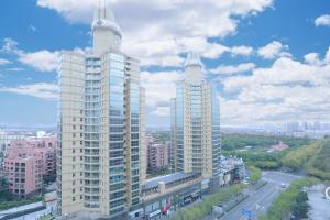 two tall white buildings in a city with a street at Green Court Residence Jinqiao Diamond Shanghai in Shanghai