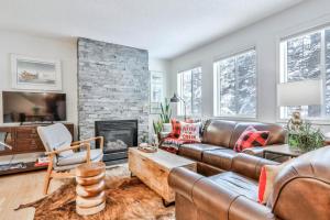 a living room with a leather couch and a fireplace at A Rustic Modern Mountain Condo - 2 bed, 2-Level in Canmore
