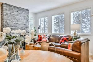 a living room with a leather couch and a table at A Rustic Modern Mountain Condo - 2 bed, 2-Level in Canmore