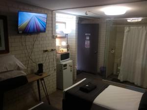a small room with a bed and a television on the wall at Kingsford Riverside Inn in Brisbane