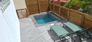 a patio with two chairs and a swimming pool at Ti Zeinga La T2 avec piscine et spa privatifs Sainte-Anne in Sainte-Anne