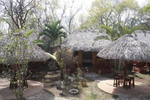 a house with two straw umbrellas and chairs and trees at Cabañas "El jardín del Edén" in Valladolid