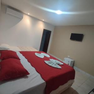 a bedroom with a bed with red and white blankets at Hotel Portal Triunfo in Triunfo