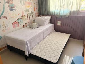 a small bedroom with a bed with white sheets at Chalé de Luxo com Piscina em Barra dos Coqueiros, Sergipe in Barra dos Coqueiros +29 photos