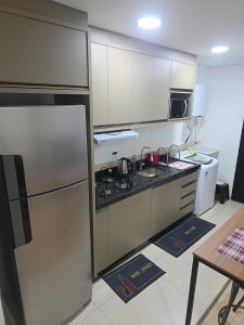a kitchen with a stainless steel refrigerator and a stove at Apartamento aconchegante e tranquilo in Foz do Iguaçu