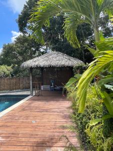 a wooden deck with a hut next to a swimming pool at LES JOYAUX DE BALATA in Saint-Joseph