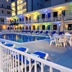 a hotel with a swimming pool with chairs and a building at Beach Colony Motel in Wildwood Crest