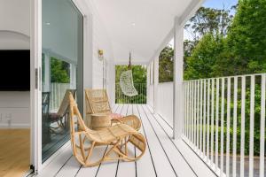 a porch with rocking chairs and a flat screen tv at Casa Scenic MacMasters Beach in Macmasters Beach