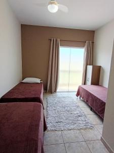 a bedroom with two beds and a large window at Refúgio Aura,casa com suíte, wi-fi, garagem e churrasqueira in Aparecida