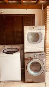 a washer and a washing machine and a microwave at Refúgio do Ipê Rosa in Tubarão