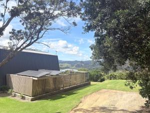 a backyard with a fence and a field of grass at Whangaroa Barn in Whangaroa