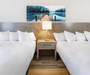 two beds in a room with a table with a lamp at Repotel Aéroport Québec in Quebec City