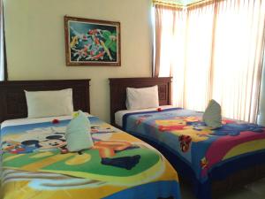 a bedroom with two beds and a painting on the wall at Lucky Paradise Bungalows on The Beach in Amed