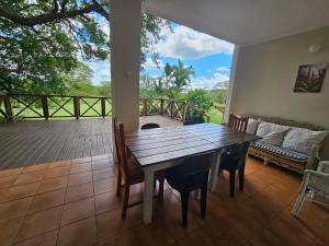 a wooden table and chairs in a room with a deck at Schuilhoek Farm House at Ngweni Private Game Farm in Hluhluwe