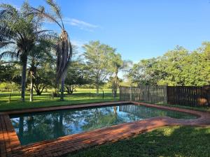 a swimming pool in a yard with trees at Schuilhoek Farm House at Ngweni Private Game Farm in Hluhluwe