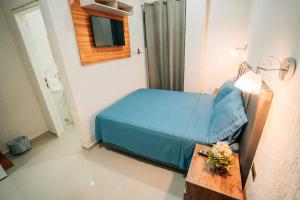 a small bedroom with a blue bed and a table at Hotel Urban Biz in Pilar +2 photos