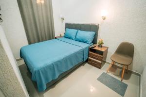 a small bedroom with a blue bed and a chair at Hotel Urban Biz in Pilar