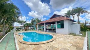 a villa with a swimming pool in front of a house at Chalé Esmeralda in Gravatá
