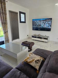 a living room with a couch and a tv on the wall at Villa Marie in Graignes