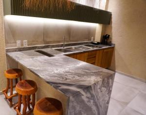 a kitchen with a marble counter top and two stools at Brisa e Sal in São Miguel dos Milagres