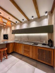 a large kitchen with wooden cabinets and a sink at Brisa e Sal in São Miguel dos Milagres