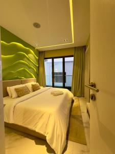 a bedroom with a white bed with a green wall at Luxury 2 Bedroom Apartment with 2 Private Patios in Lekki Phase 1 in Lekki