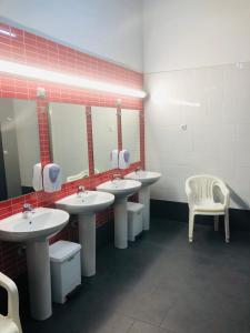 a public bathroom with four sinks and a white chair at All Iron Hostel in Bilbao +59 photos