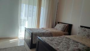 a bedroom with two beds and a flat screen tv at maison achab in Asilah