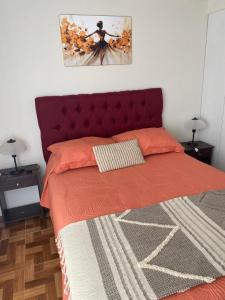 a bedroom with a bed with an orange comforter and two lamps at Alojamiento Parque Libertad in La Serena