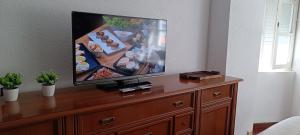 a flat screen tv sitting on top of a wooden dresser at Apartamento en Avilés Céntrico & Parking in Avilés