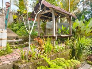 a wooden gazebo in a garden with plants at Nostalgia Camping Home 1 in Selemadeg