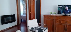 a living room with a television and a white chair at Apartamento en Avilés Céntrico & Parking in Avilés