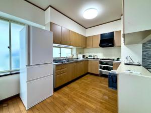 a kitchen with a white refrigerator and wooden cabinets at mahoratto inn in Aomori