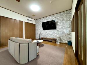 a living room with a couch and a tv on a brick wall at mahoratto inn in Aomori